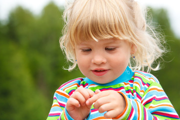 Portrait of little girl in stripe clothe with earrings in park.