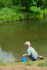 The boy with a net on the bank of lake