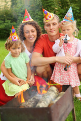 Happy family near brazier on picnic, happy birthday