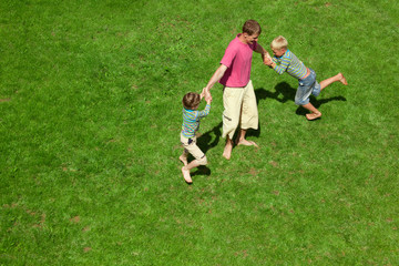 Two boys play with the adult a lawn. The top view.