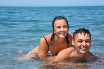 Fototapeta premium young woman sitting astride man in sea near coast