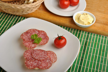 slice poppy seed bread with salami on a plate