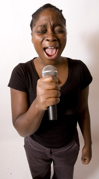 jeune femme noire chante dans un micro emotion