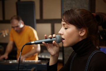 vocalist girl in studio. keyboard player in out of focus