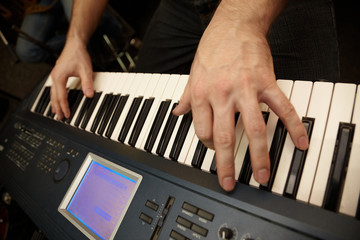 hands of musician on keys. focus on big finger of left hand
