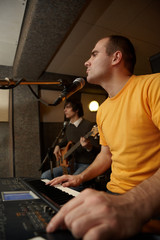 keyboarder is playing. guitar player in out of focus