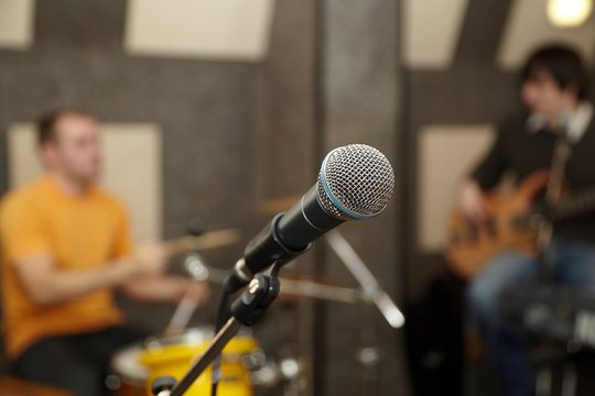 microphone. drummer and guitar player in out of focus