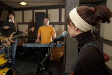 singer. focus on head of microphone. musicians in out of focus
