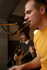 keyborder is playing and singing. guitar player in out of focus