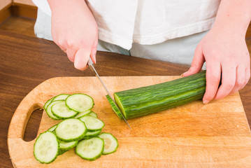The girl cuts a cucumber