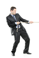 A young businessman pulling a rope isolated on white