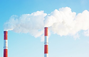 Two smoke stacks on sky background