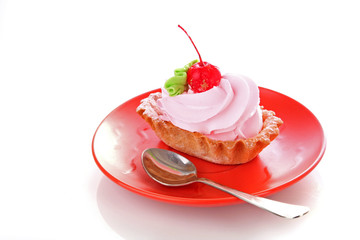 Pink cheesecake with maraschino cherry  on white