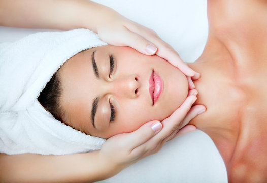 Beautiful young woman receiving facial massage.