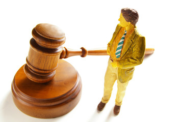 business man or attorney figure standing next to a gavel
