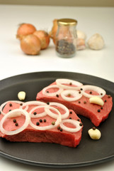 raw organic steak with onion in a pan