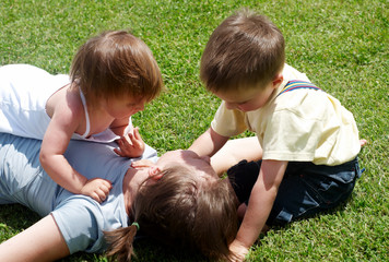 Happy mother playing with children on a lawn