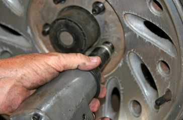 Mechanic uses impact wrench on car wheel