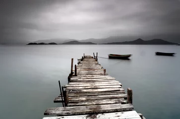 Selbstklebende Fototapeten Blick auf einen trostlosen Peer und ein Boot © leungchopan