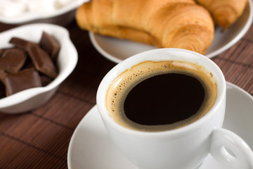 Cup of coffee served with croissants and chocolate