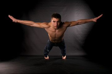 Dramatic light photo of modern acrobat in front of black backgro