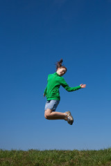 Girl running, jumping against blue sky