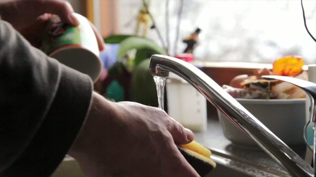 Mann sp&uuml;lt Geschirr
