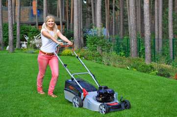 Young woman working in a garden mowing the lown