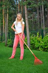 Young woman working in a garden with rakes