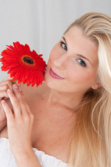 Young healthy woman with pure skin and red flower