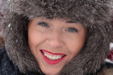 Young woman in fur hat smilling on the snow