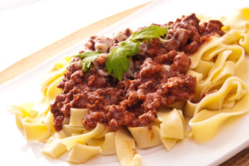 spaghetti bolognese with cheese on white plate