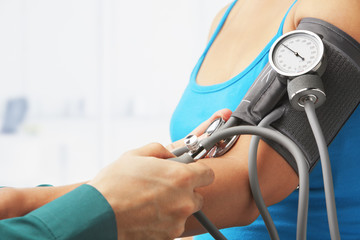 Checking blood pressure of female patient