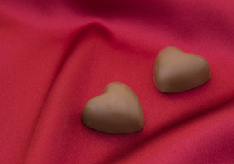 Obraz premium Chocolate hearts on red satin