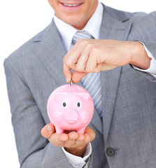 Close-up of a businessman saving money in a piggybank