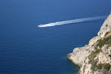 A boat with wake in front of a reef in Tuscany