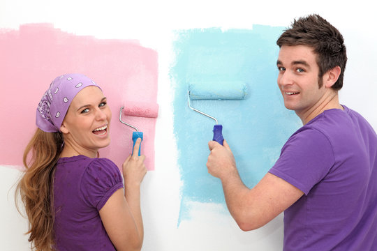 Young Couple Painting And Decorating New Home