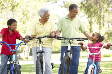 Grandparents In Park With Grandchildren Riding Bikes