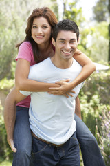 Obraz premium Young Man Giving Woman Piggyback Outdoors