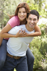 Obraz premium Young Man Giving Woman Piggyback Outdoors