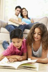 Family Sitting On Sofa At Home With Laptop