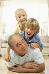 Obraz premium Grandfather Playing With Grandchildren At Home