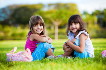 Two young smiling girls sitting in the grass