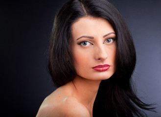 Fototapeta premium Beautiful young woman face over dark background