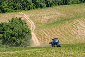 Fototapeta premium Tractor in a field in early summer