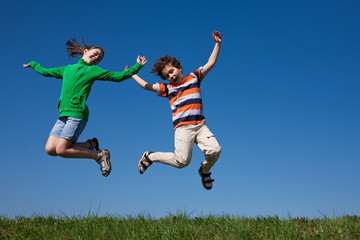 Fototapeta na wymiar Kids jumping, running against blue sky