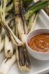 Grilled spring onions in romesco sauce. Spanish cuisine. Calçots