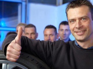 Tyre master mechanic in front of his assembly mans showing thumb