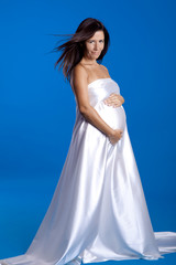 Fototapeta na wymiar Beautiful pregnant woman posing over a blue background
