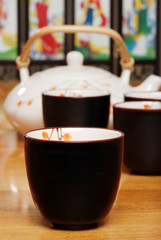 closeup asian tea cup with set in the background
